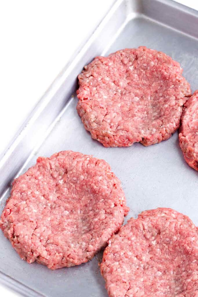 hamburger patties on a baking tray