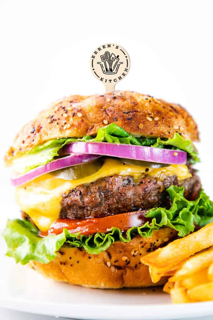 a hamburger made with The Best Hamburger Recipe piled high with toppings and a cocktail stick through the bun