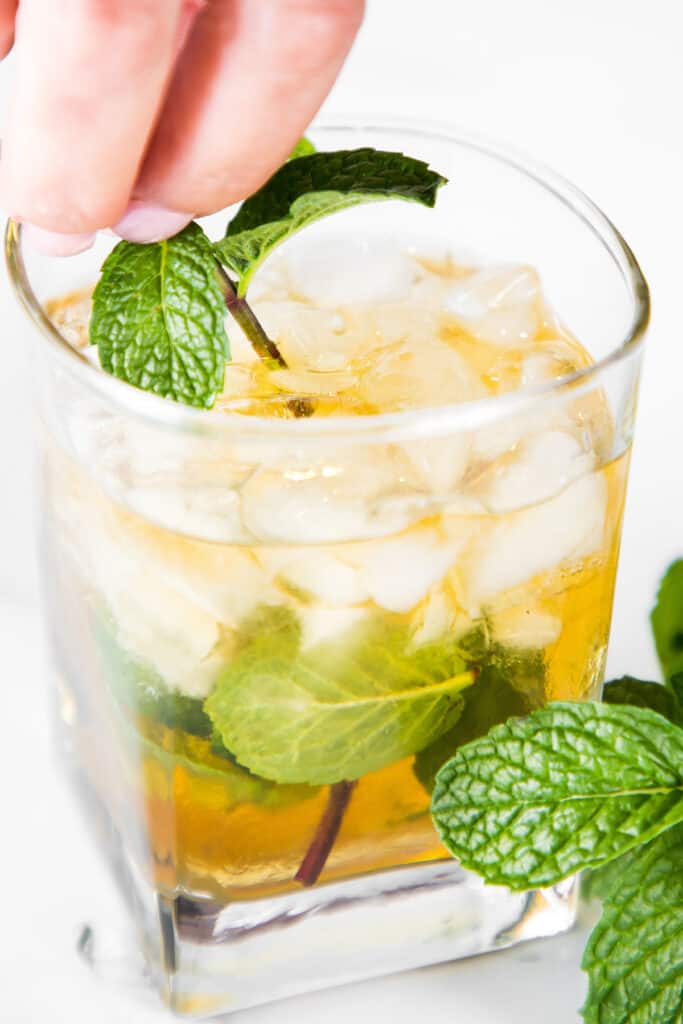 a sprig of mint being placed in a Mint Julep Cocktail