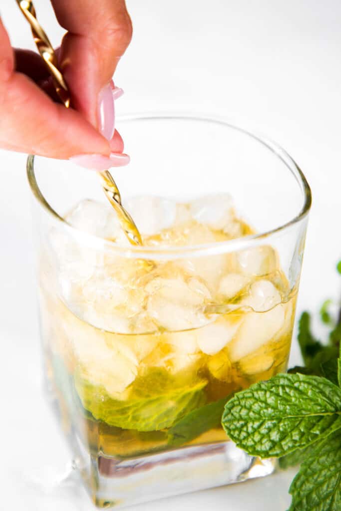 the Mint Julep Cocktail mixture being stirred in a glass