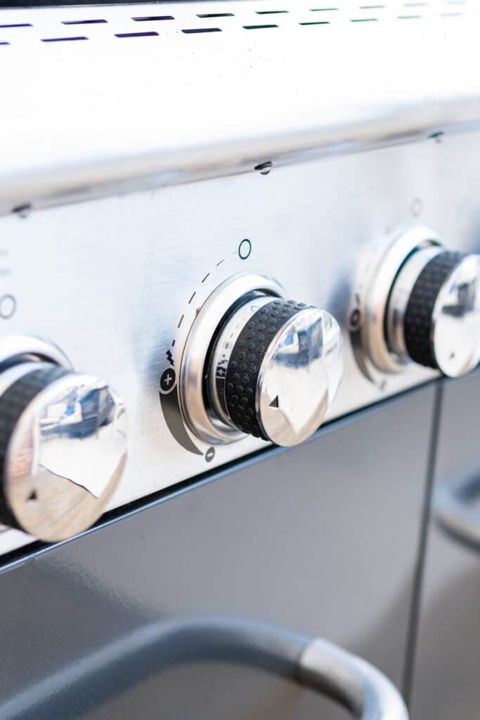 Close up of control knobs on an outdoor gas grill.