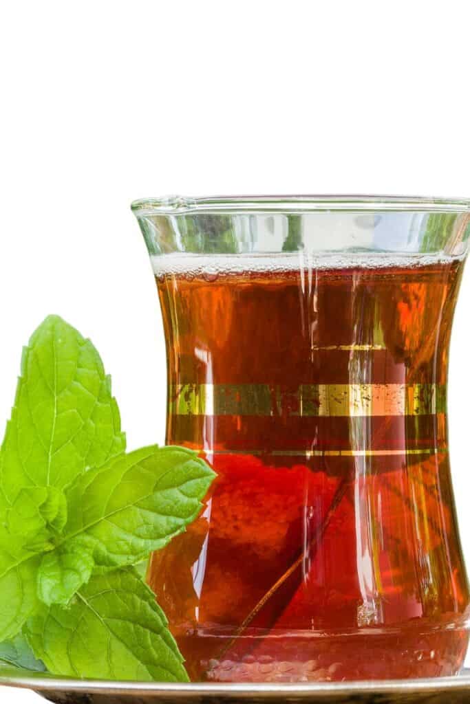 a  pot of mint tea with mint leaves next to it.