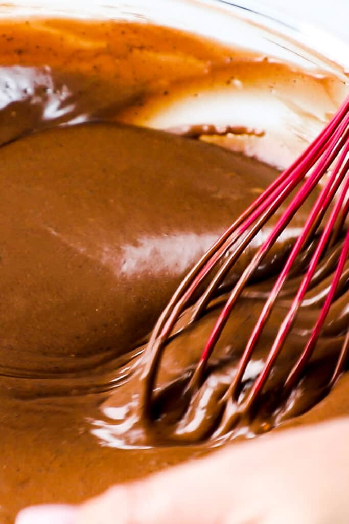 a whisk mixing the dark chocolate ice cream mixture in a bowl
