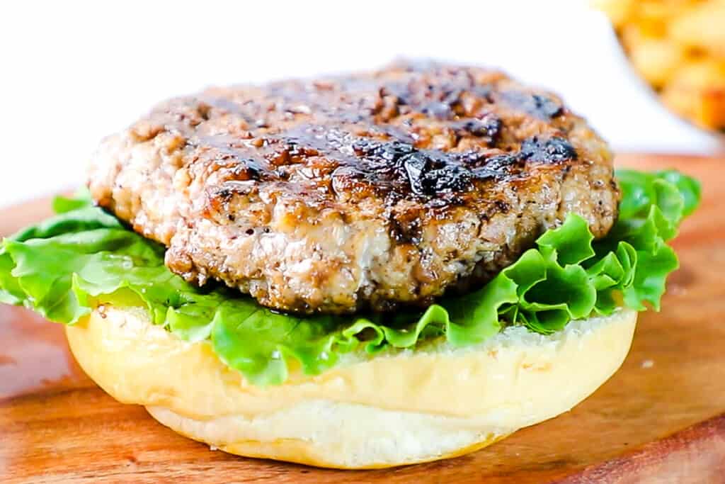 a pork burger on a bun with lettuce