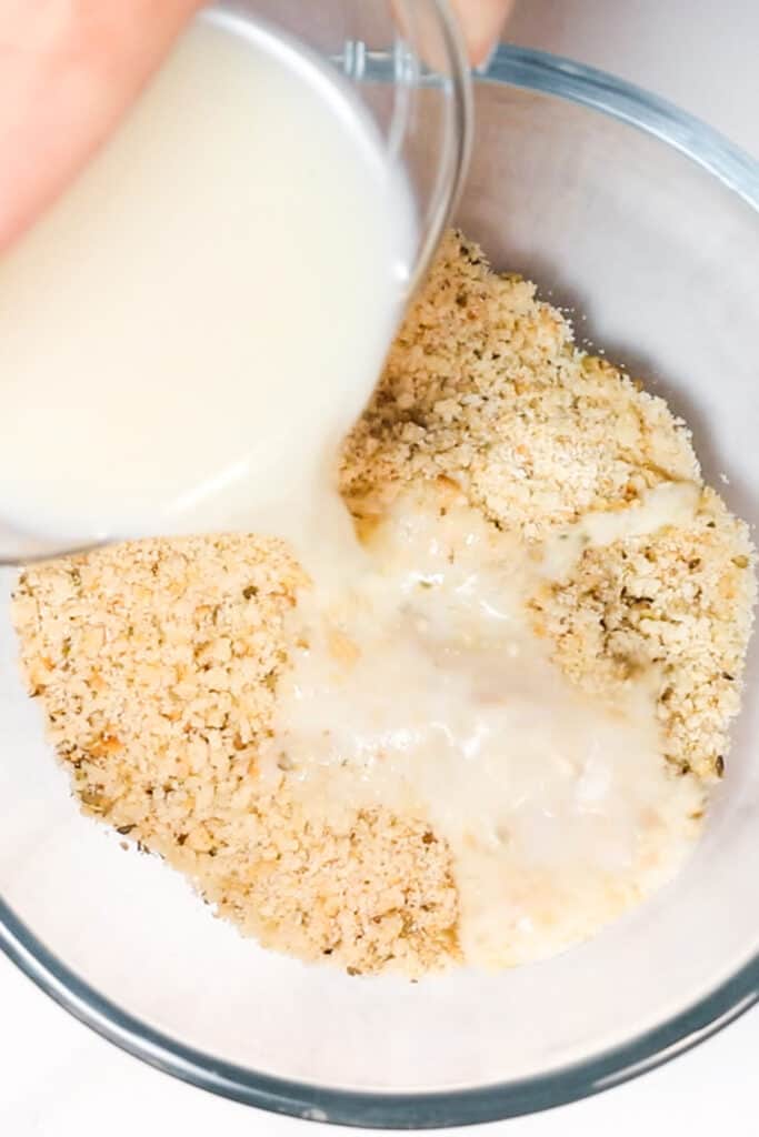 milk being poured into a bowl of breadcrumbs