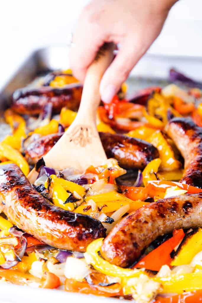 Italian Sausage and Peppers being scooped off a sheet pan