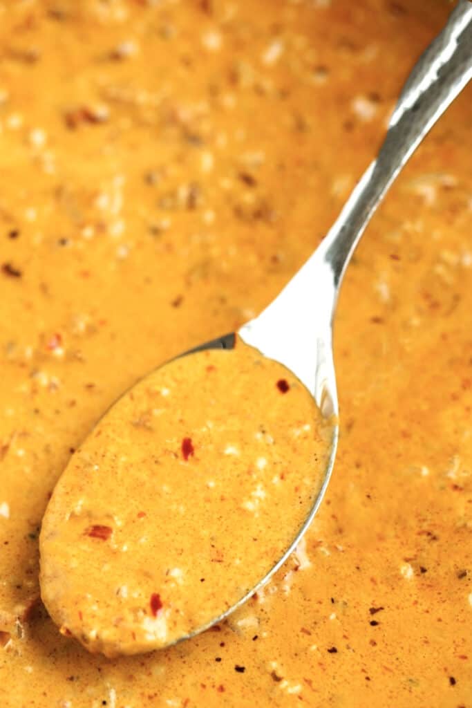 A spoonful of the sauce cooking in the pan