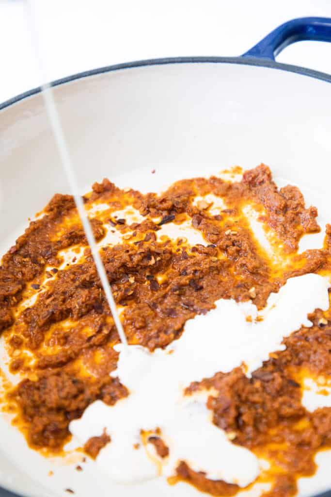 cream being added to the pan with the pesto mixture