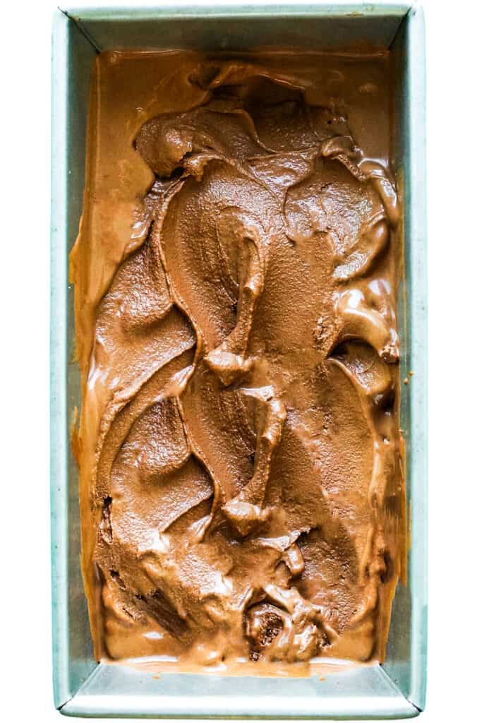 el helado de chocolate oscuro esparcido en un molde para pan de metal
