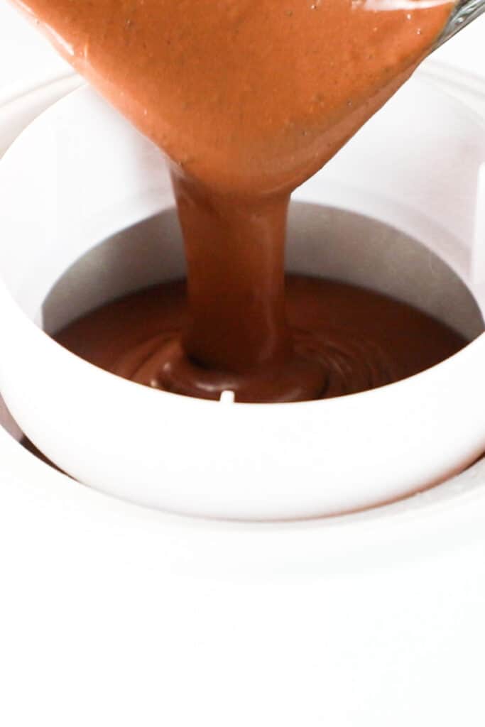 the dark chocolate ice cream mixture being poured into an ice cream maker