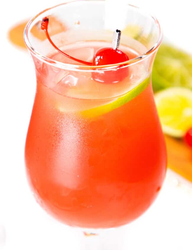 a sea breeze cocktail in a stemmed glass garnished with a lime slice and cherry