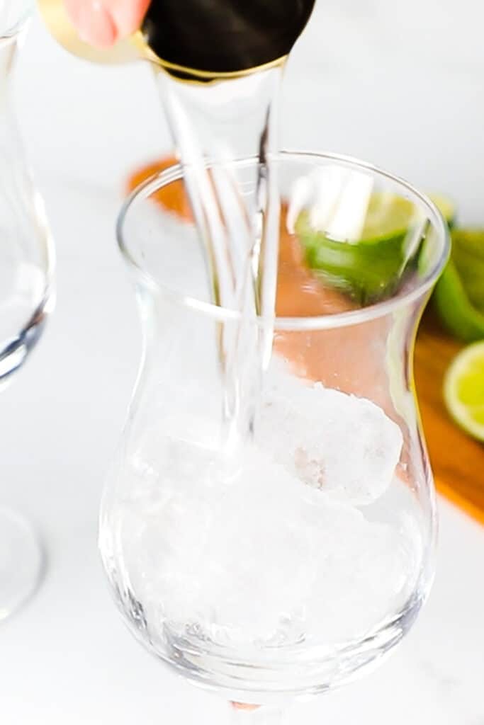 vodka being poured into a glass with ice