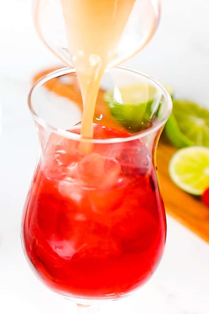 grapefruit juice being poured into the cranberry and vodka mixture