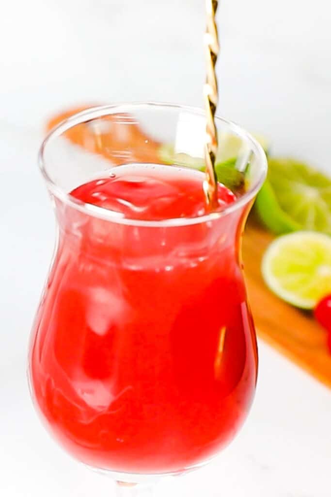 a cocktail stirrer mixing a sea breeze cocktail