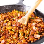 Homemade BBQ Baked Beans in a pan with a serving spoon