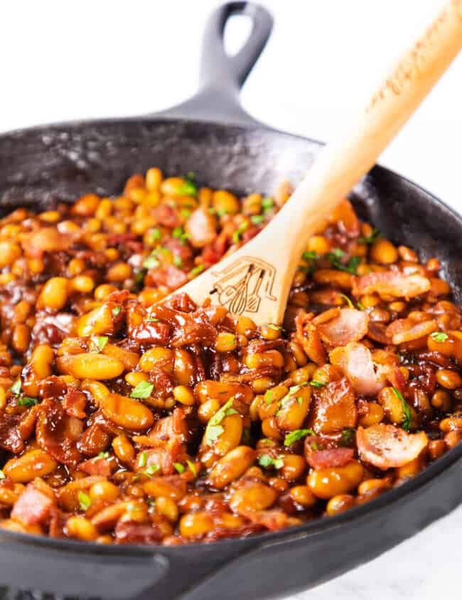 Homemade BBQ Baked Beans in a pan with a serving spoon