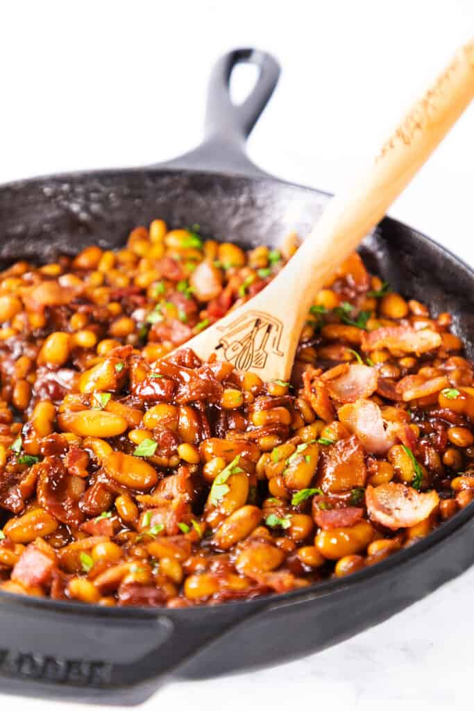 Homemade BBQ Baked Beans in a pan with a serving spoon