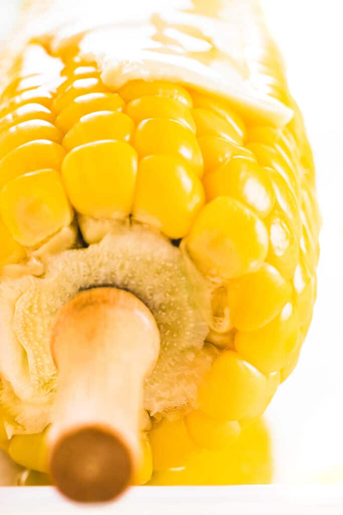 a close up shot of an ear of corn on the cob topped with butter