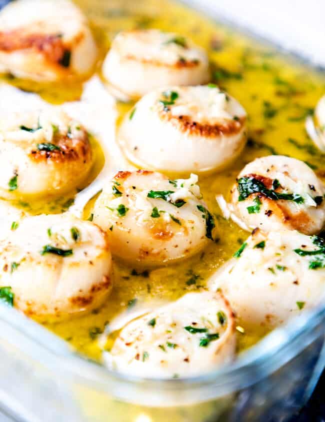 a glass dish with broiled scallops with garlic butter