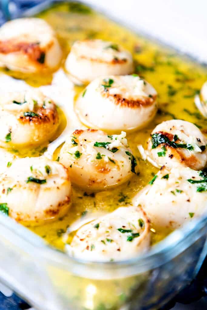 a glass dish with broiled scallops with garlic butter