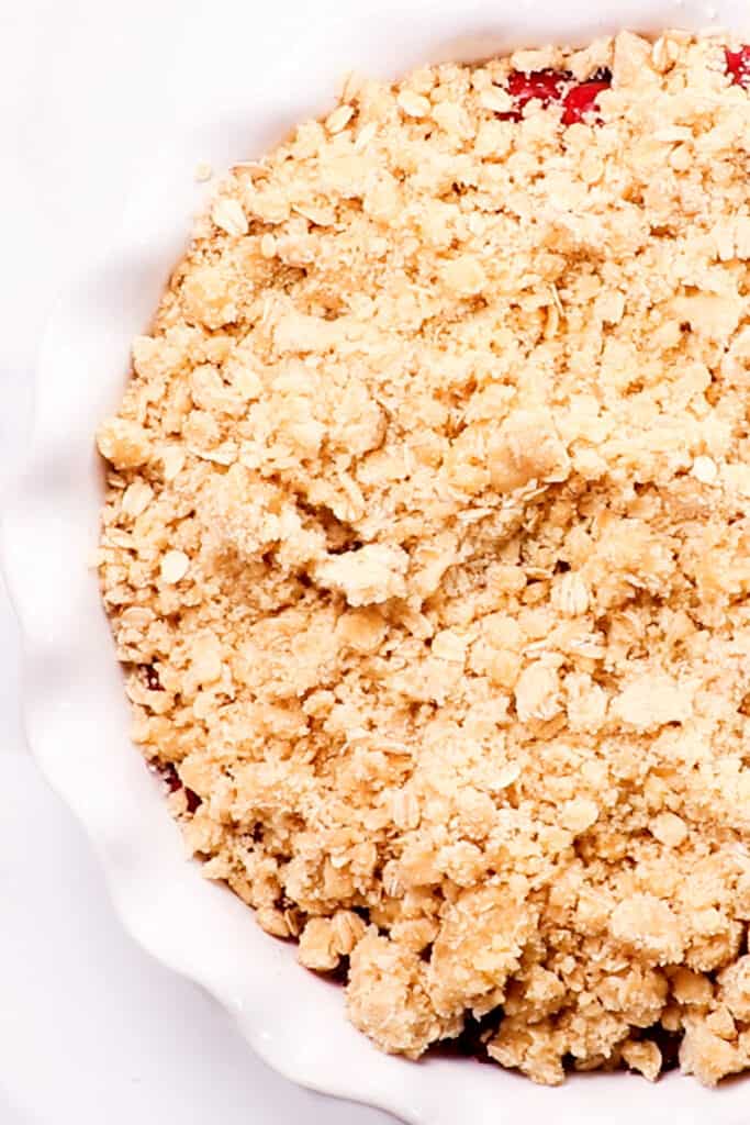 la cobertura Cherry Crumble esparcida sobre el relleno en el molde para pastel