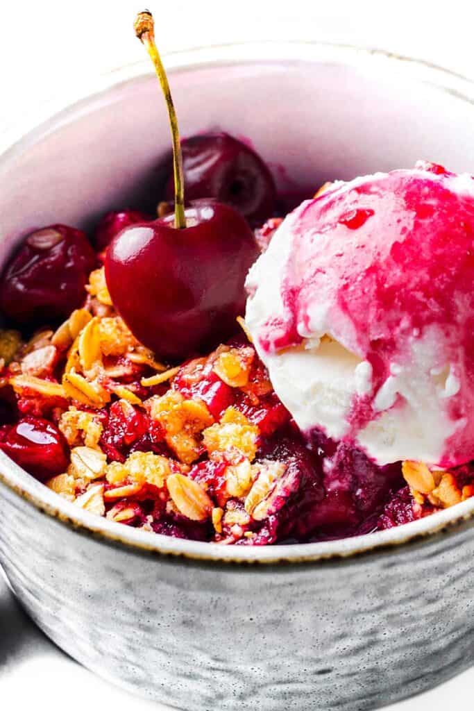 Crumble de cereza con helado en un tazón.