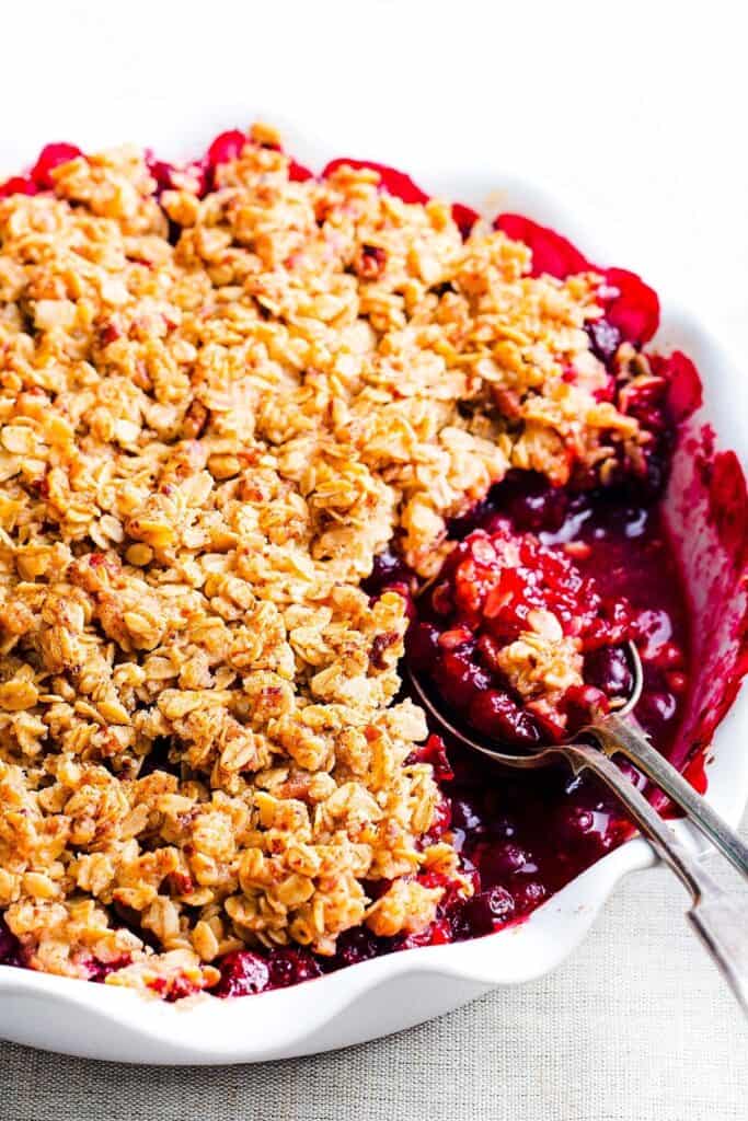 Cherry Crumble con una porción extraída que muestra el relleno y dos cucharas en el plato