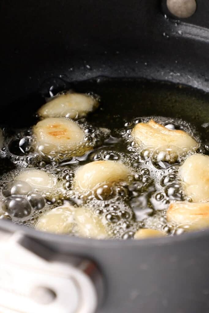 garlic cloves cooking in oil