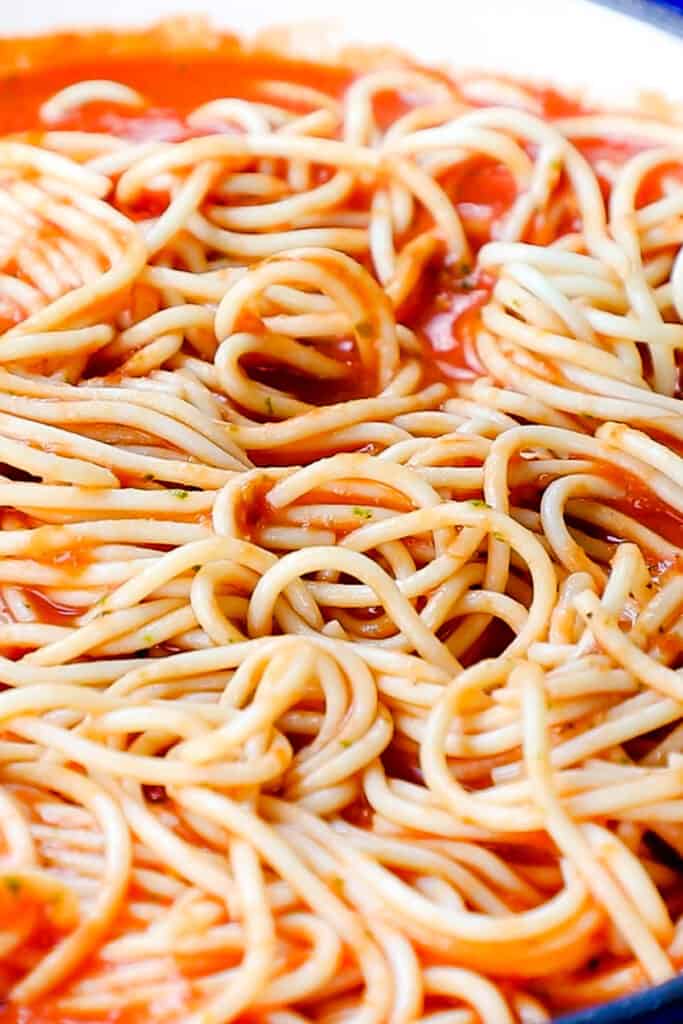 the spaghetti added to the sauce in the pan