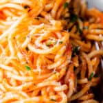 a plate of spaghetti with tomato sauce and a fork next to it