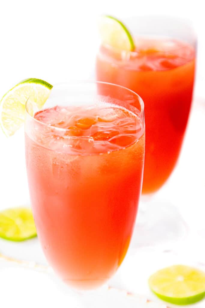 two glasses of two bay breeze cocktail with a lime wedge on the glass