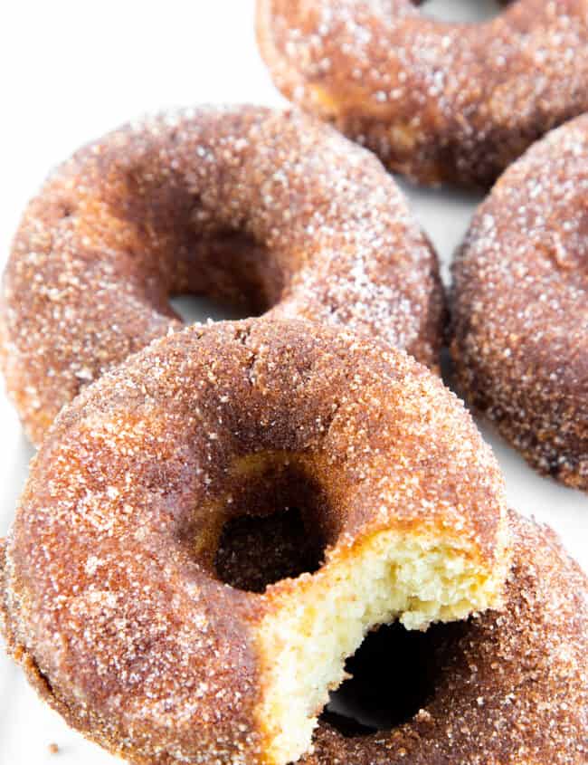 a pile of Cinnamon Sugar Donuts with one missing a bite