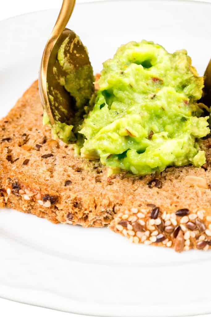 Guacamole being spooned onto toast