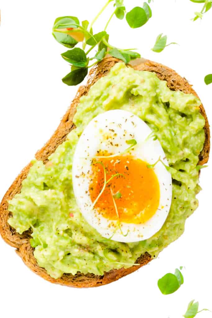 Guacamole Toast topped with a soft boiled egg and some greens