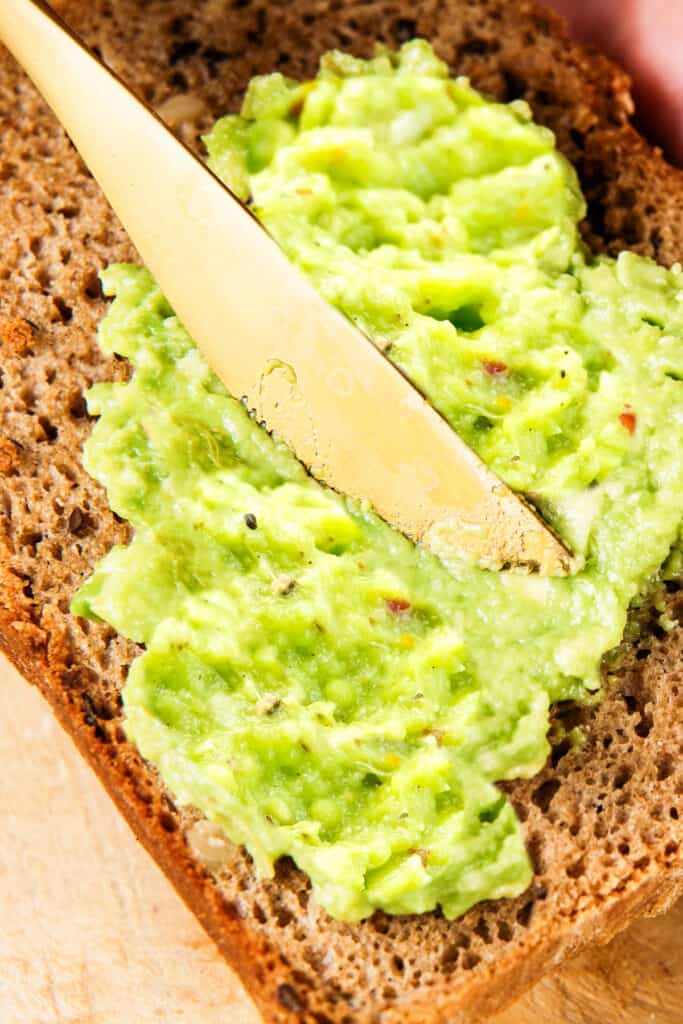 Guacamole being spread onto toast