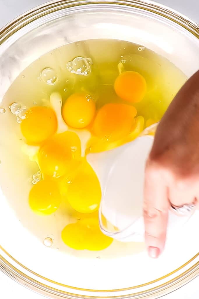 cream being poured into eggs in a bowl