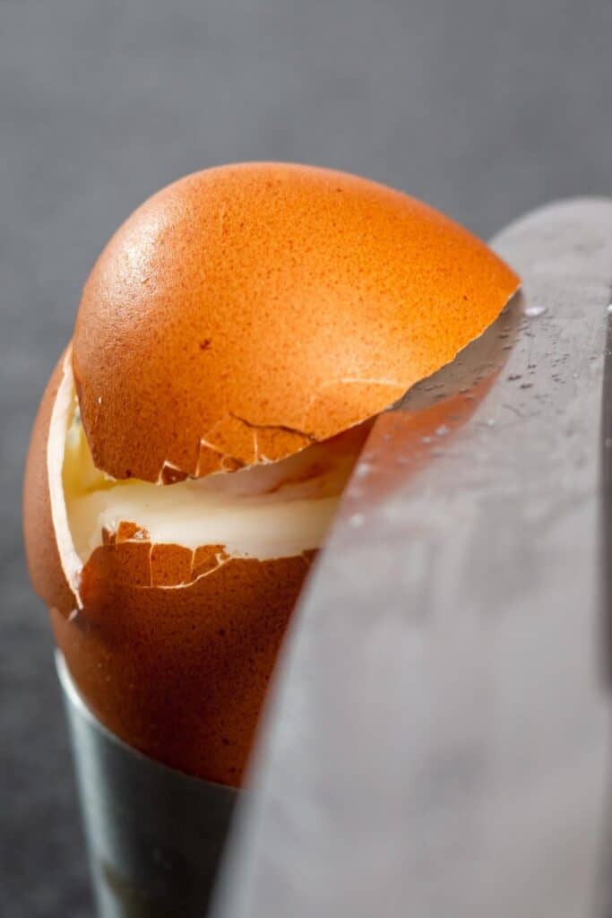 un cuchillo cortando la parte superior de un huevo cocido