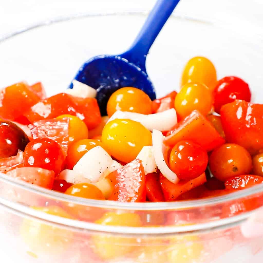 tomatoes, onions and garlic coated with olive oilin a mixing bowl 