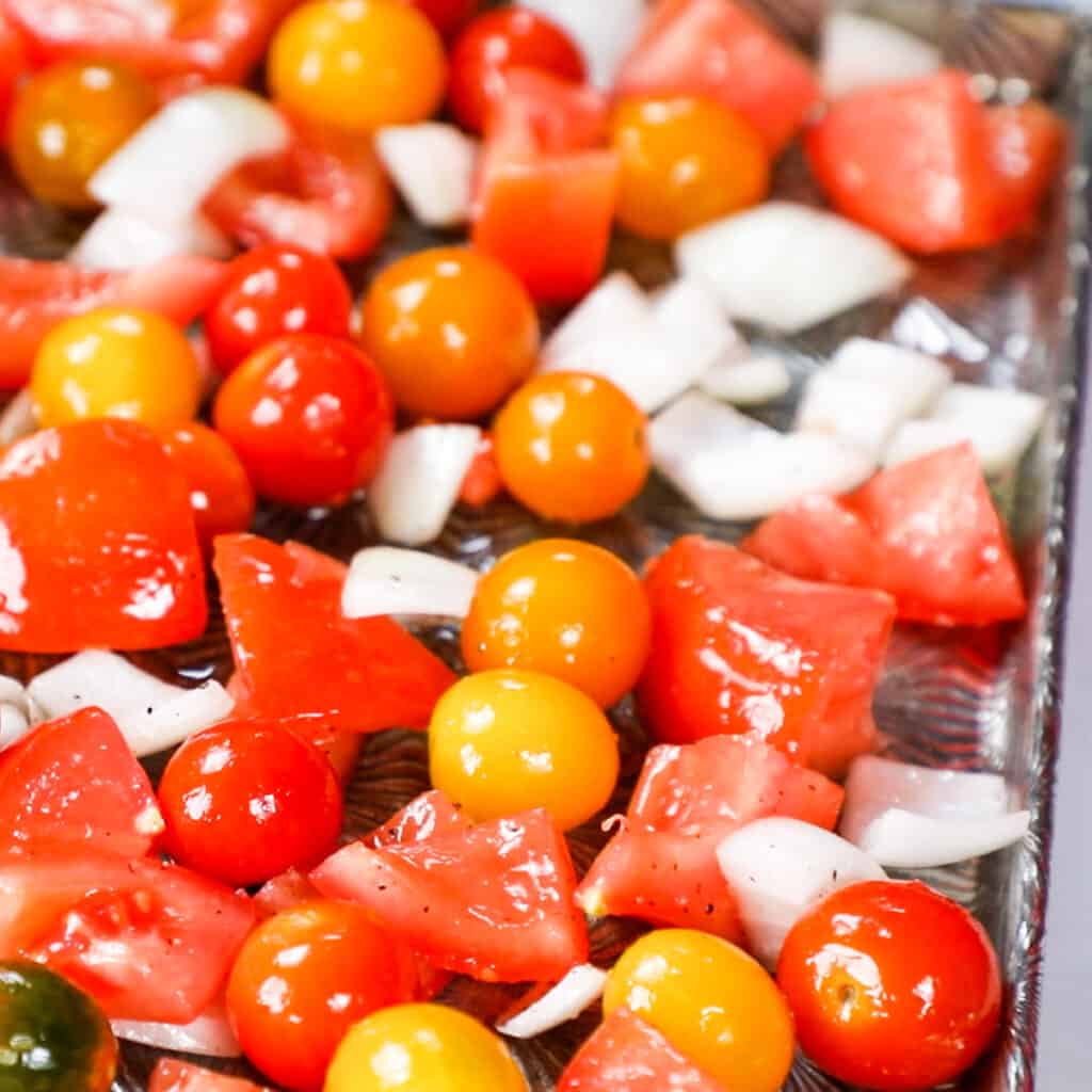 a pan with tomatoes, onions and garlic cloves