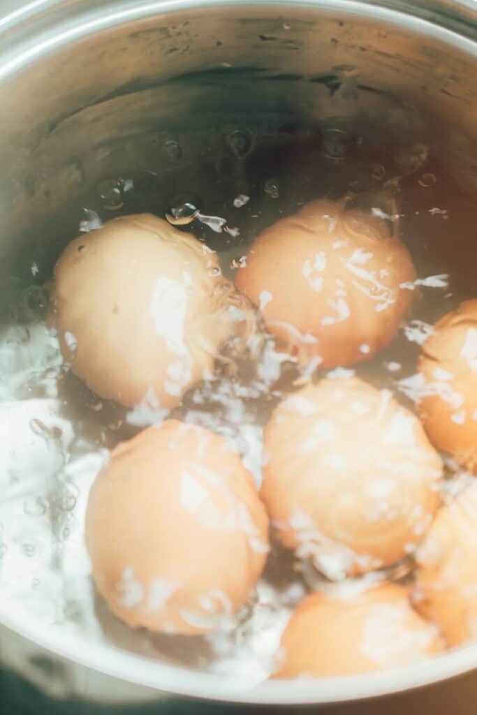 brown eggs boiling in a pot of water