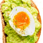 Toast with Guacamole and soft boiled egg on white tray, liquid yolk, delicious breakfast, light sandwich. Healthy food