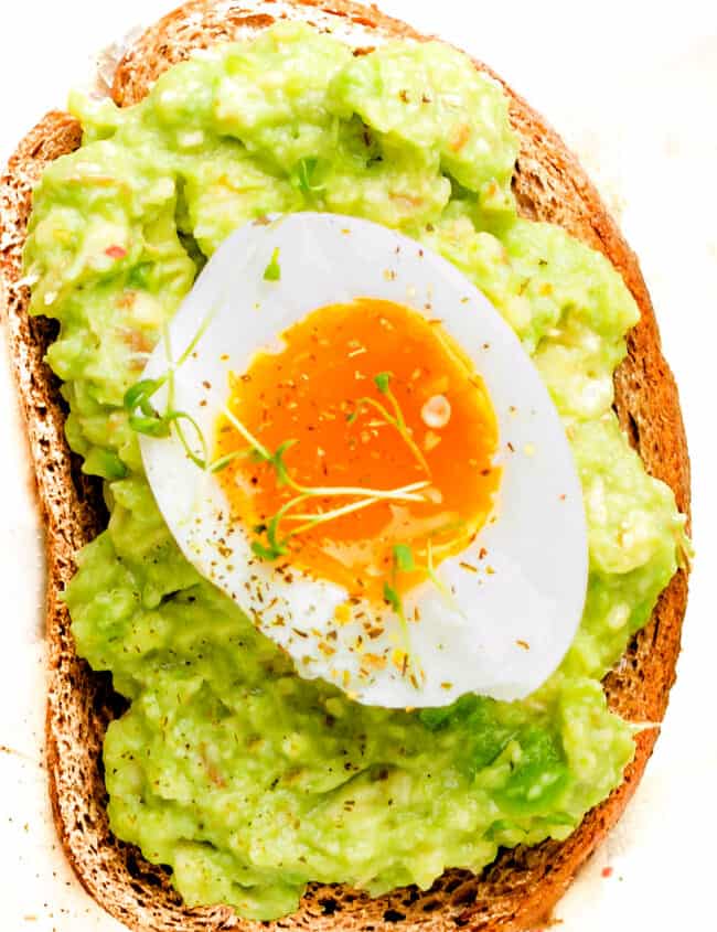 Toast with Guacamole and soft boiled egg on white tray, liquid yolk, delicious breakfast, light sandwich. Healthy food