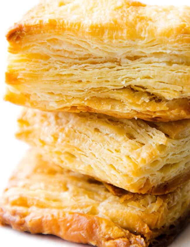 a close up image of three slices of baked, golden rough puff pastry