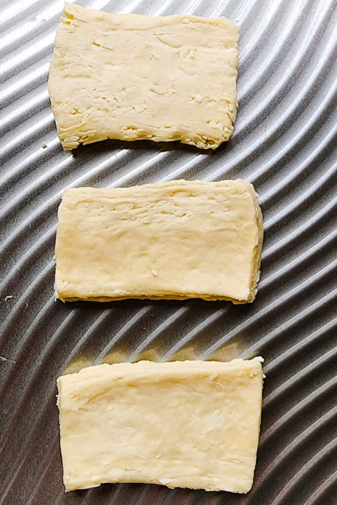 three rolled out squares of dough on a baking sheet