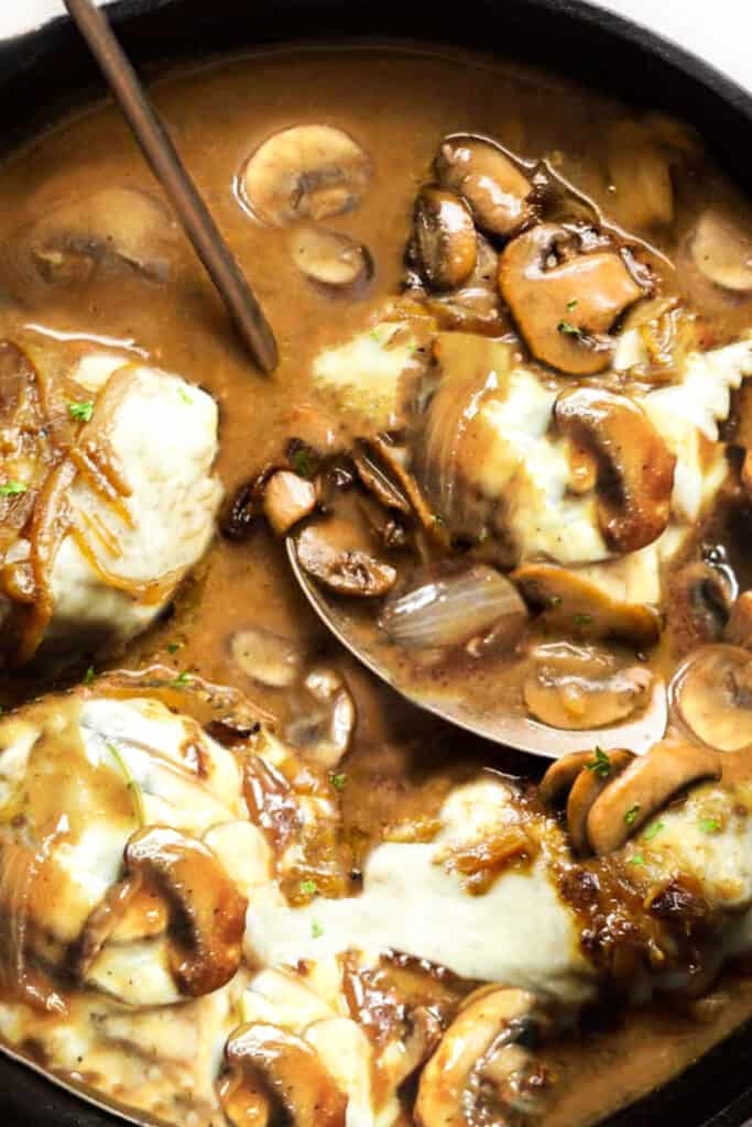 Smothered Pork Chops covered with white cheese in a mushroom gravy