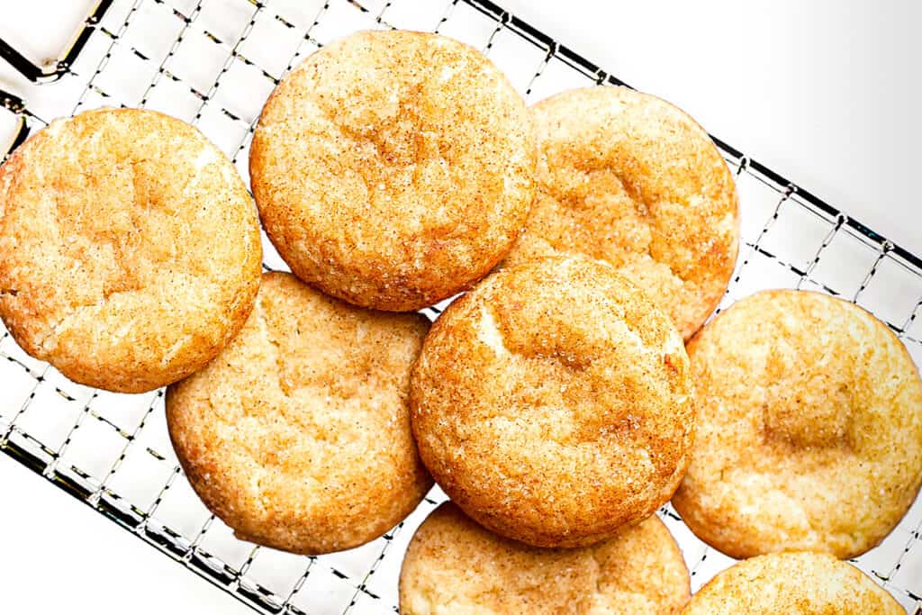 Snickerdoodles stacked on a cooling rack.