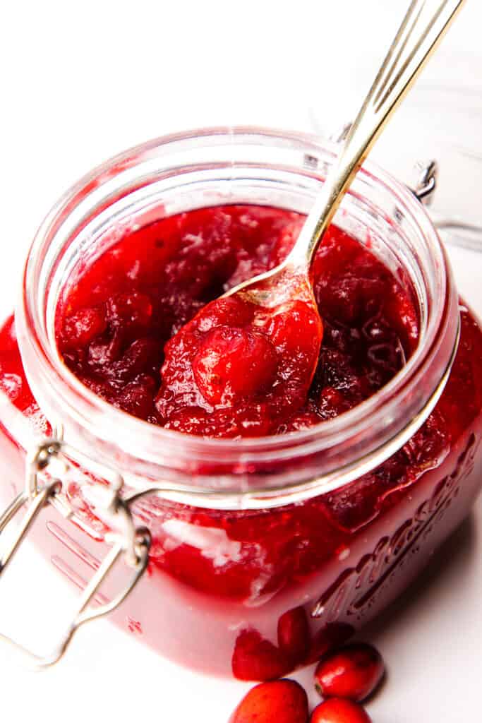 Homemade Fresh Cranberry Sauce in a jar with a spoon