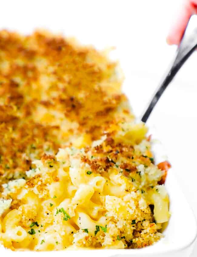 A pan of Creamy Baked Mac & Cheese with a spoon scooping out a portion from the pan