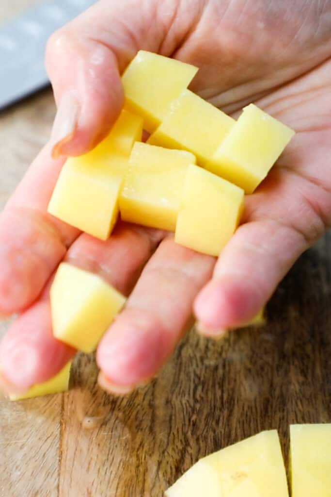 a woman holding potato cubes