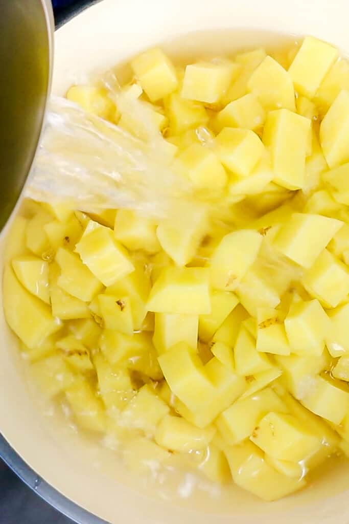 boiling water being poured over a pot of potatoes